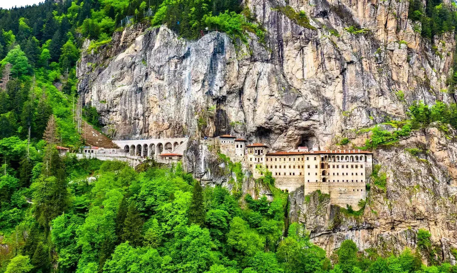 DDD Invoices supporting fiscalisation in Turkey, featuring the Sumela Monastery built into a steep cliff surrounded by lush forested mountains.