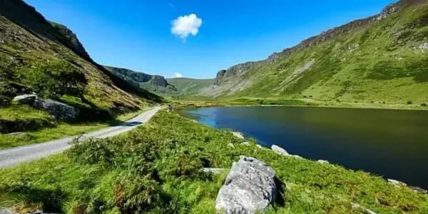  Peaceful Irish countryside with rolling green hills, a lakeside path, and clear blue sky, reflecting natural harmony and the reliability of DDD Invoice.