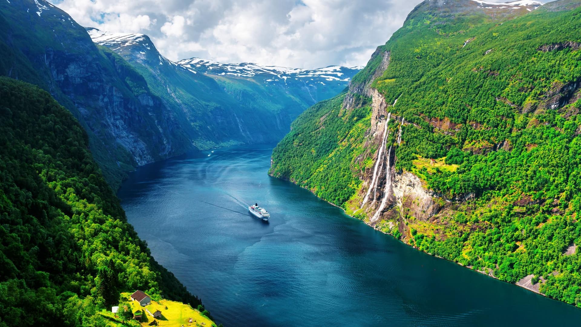 Evening view of a Norwegian fjord with steep green mountains, cascading waterfalls, and a cruise ship sailing through calm waters, symbolizing Norway’s advanced digital invoicing ecosystem supported by DDD Invoices’ API solution.