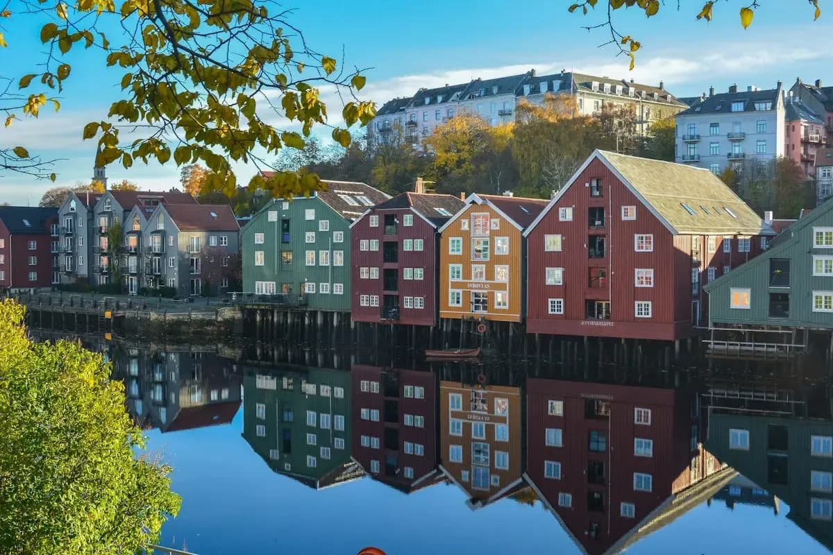 Colorful riverside buildings in Norway reflected on calm water, representing the country’s digital invoicing environment supported by DDD Invoices.