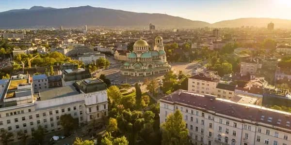 Vibrant cityscape of Sofia, Bulgaria, with colorful buildings, parks, and mountain views, showcasing the modernization of business processes supported by DDD Invoices’ e-invoicing solutions in Bulgaria.