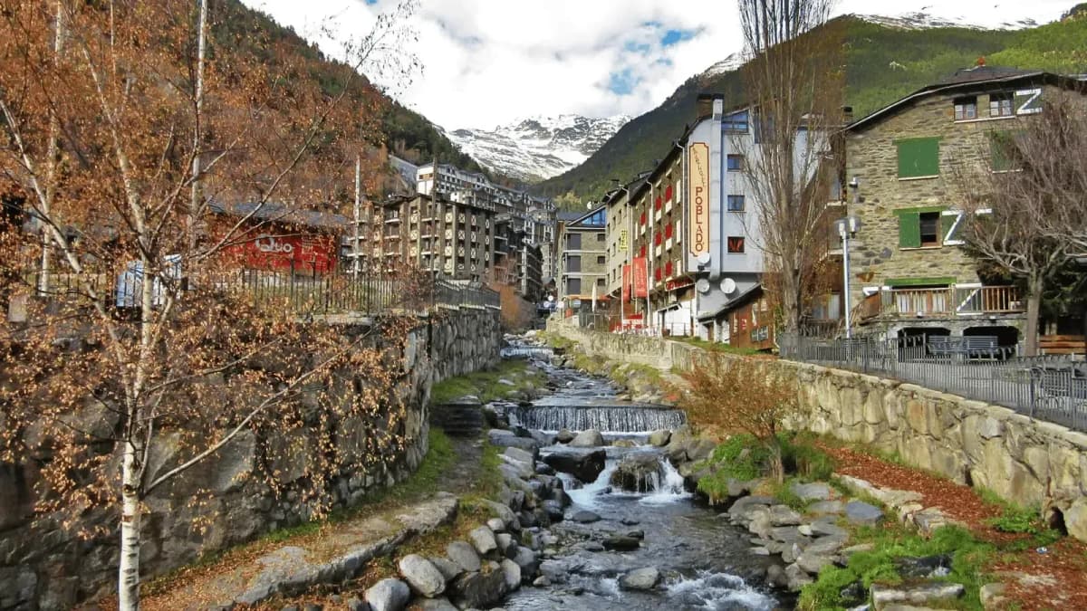 DDD Invoices supporting fiscalisation in Andorra, with a scenic mountain village view featuring a small river, stone buildings, and alpine surroundings.