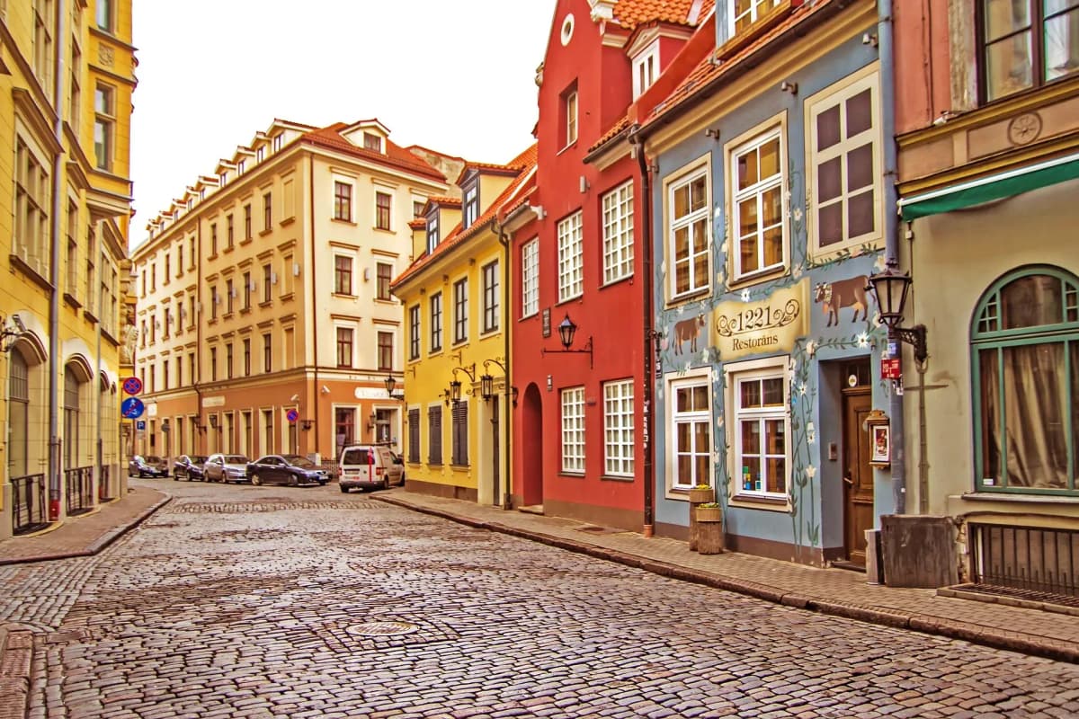 DDD Invoices supporting e-invoicing in Latvia, featuring a charming old town street with colorful buildings and cobblestone road.