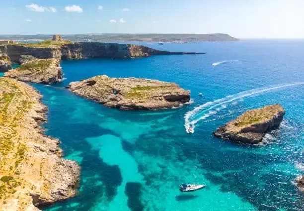 DDD Invoices fiscalization and e-invoicing compliance illustrated by a turquoise coastal bay with boats and limestone cliffs in the Blue Lagoon, Comino, Malta