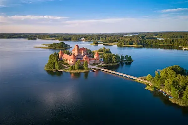 Aerial view of a Lithuanian city at sunset, with a wide river flowing through the center, symbolizing digital connectivity and cross-border e-invoicing solutions supported by DDD Invoices.
