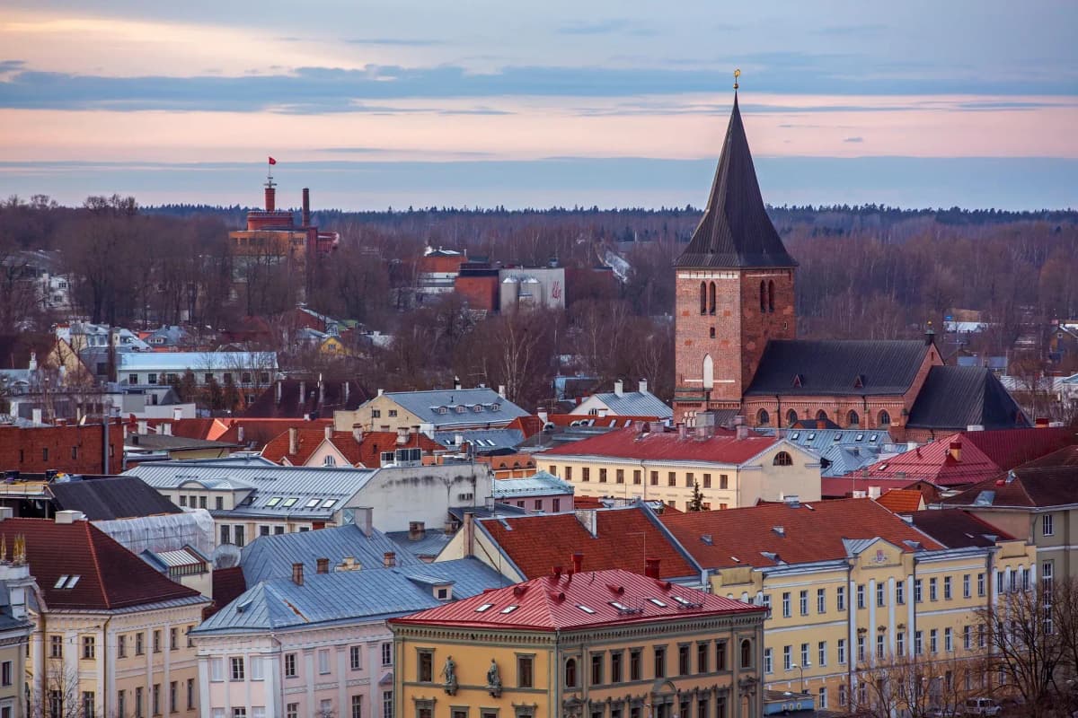 DDD Invoices supporting e-invoicing in Estonia, featuring a historic cityscape with red-roofed buildings and a tall brick church tower at dusk.