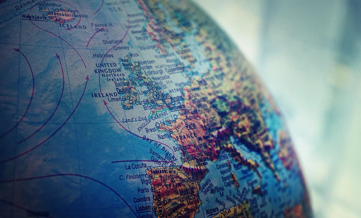 Close-up view of a globe showing part of Western Europe, with country names, major cities, and geographical features visible.