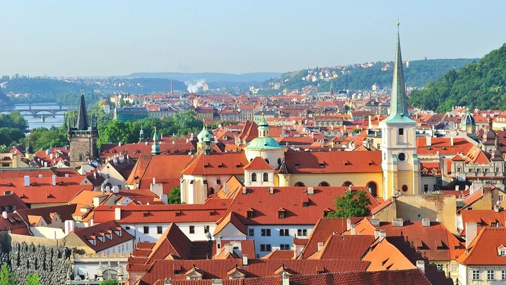 Panoramic view of Prague’s historic cityscape with red-roofed buildings, church towers, and bridges across the Vltava River, used by DDD Invoice in an article about e-invoicing and fiscalization developments in the Czech Republic.