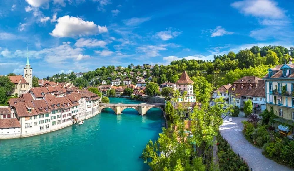A scenic view of Bern, Switzerland, with the turquoise Aare River, historic bridge, and traditional Swiss houses, as the country enhances its digital transformation journey with DDD Invoices API solutions for streamlined e-invoicing.