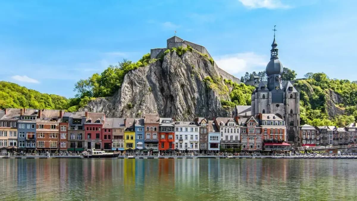 DDD Invoices supporting fiscalisation in Belgium, with colorful riverside houses and a historic church set against dramatic cliffs along the Meuse River