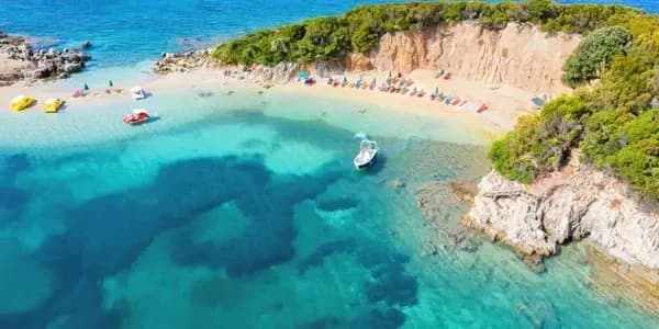 Crystal-clear coastal cove in Albania with boats and a sandy beach, as the country moves toward mandatory e-invoicing supported by DDD Invoices’ API solution.