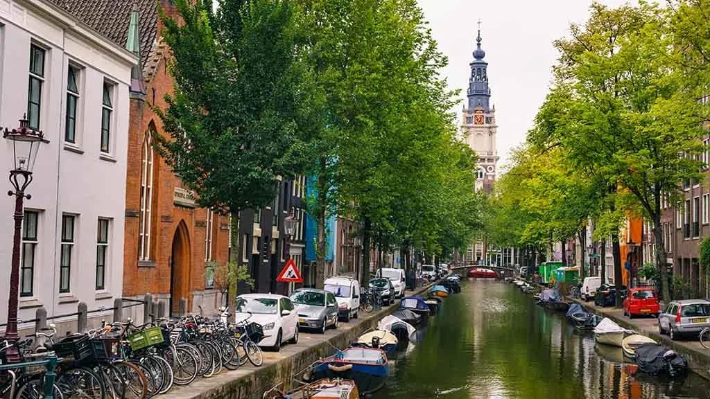 Iconic evening canal view in Amsterdam, Netherlands, with historic architecture, bicycles, and boats illuminated by streetlights, supported by DDD Invoices for seamless digital invoicing experiences.