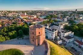 Aerial view of a historic Lithuanian city with red-tiled rooftops, church towers, and green spaces, representing Lithuania’s evolving business landscape and digital invoicing environment supported by DDD Invoices.